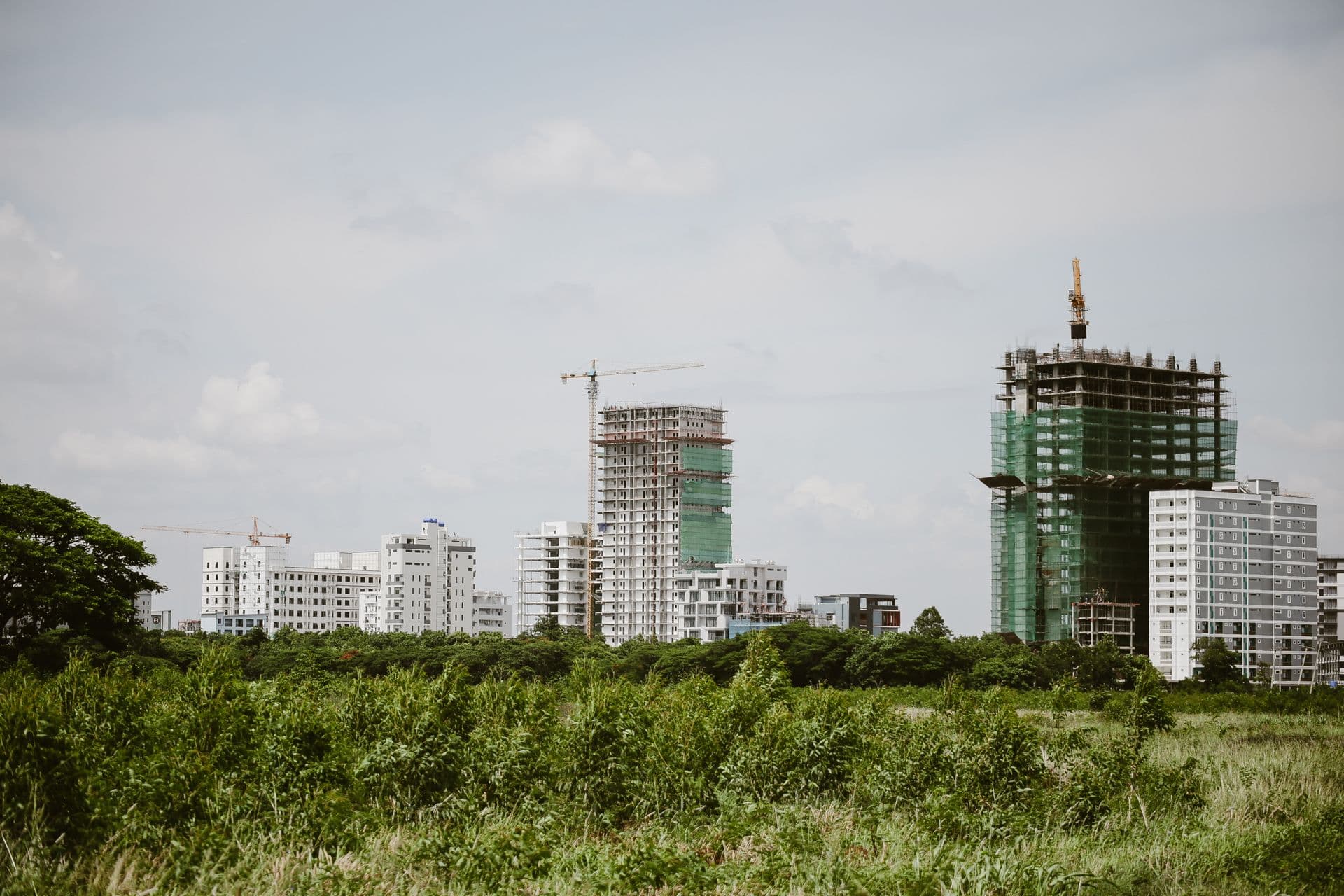 City skyline with several tower cranes above buildings under construction, black-and-white photograph — illustrative image for the demo
