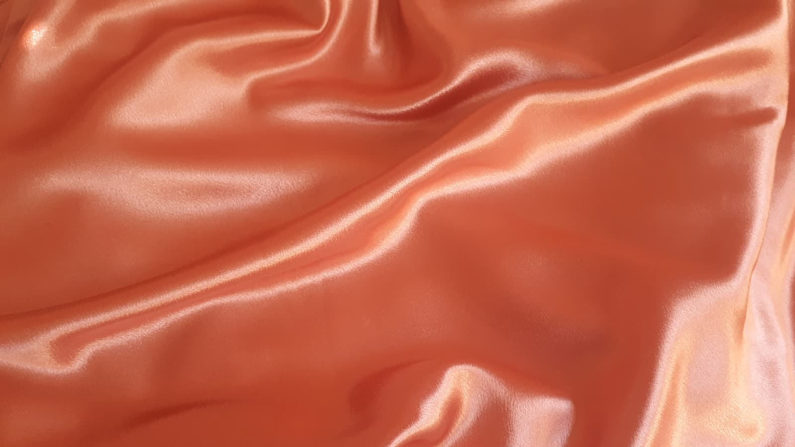 Draped copper and terracotta silk fabric with soft folds and shadow